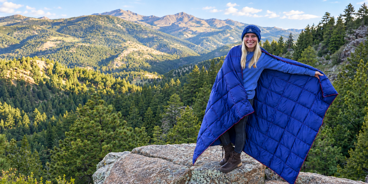 Woman wearing a blue Get Out Gear camping blanket on a mountain overlook
